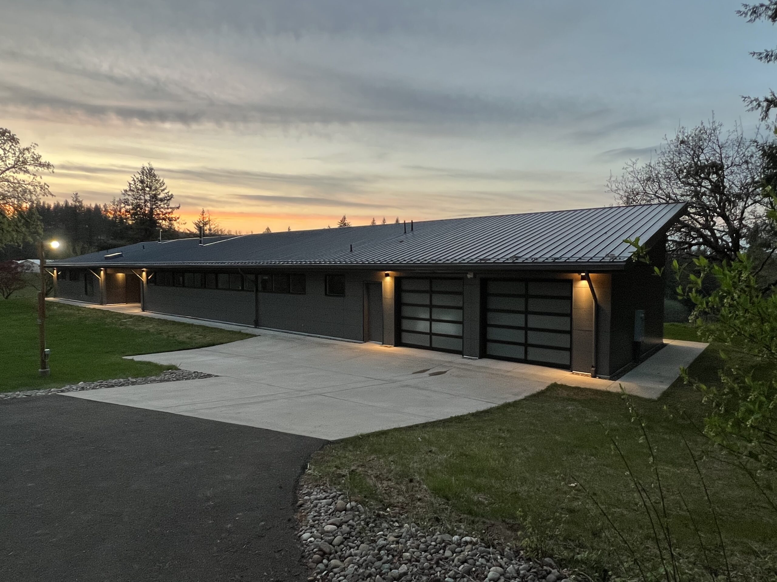 photo of a driveway and home with garage and sloped roof at dusk